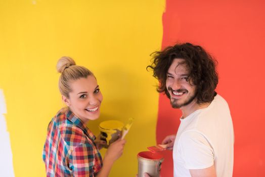 happy smiling young couple painting interior wall of new house