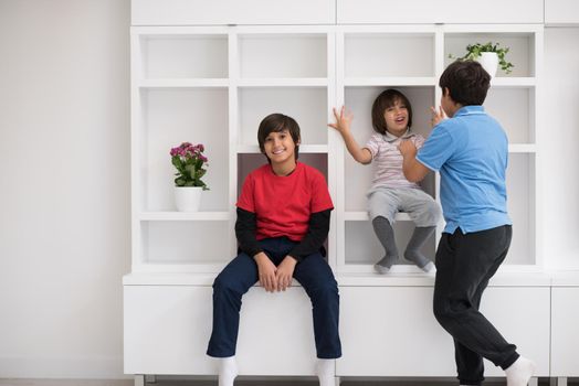 happy young boys are having fun while posing on a shelf in a new modern home