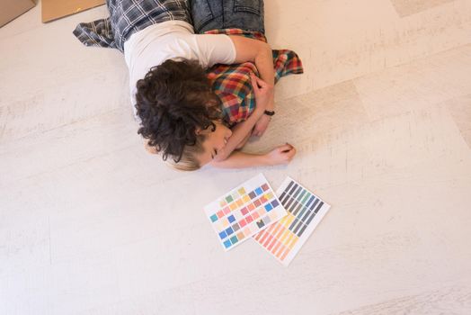 Happy young couple relaxing after painting a room in their new house on the floor