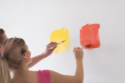 happy smiling young couple painting interior wall of new house