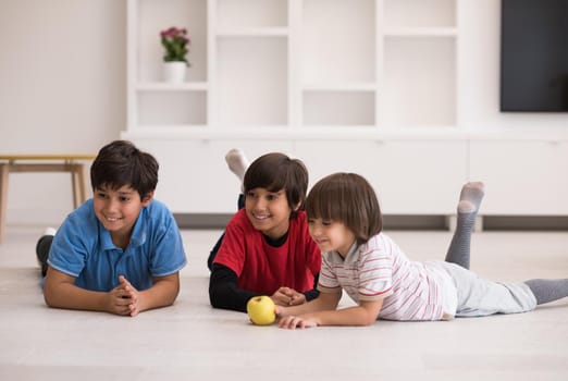 happy young boys having fun with an apple on the floor in a new modern home