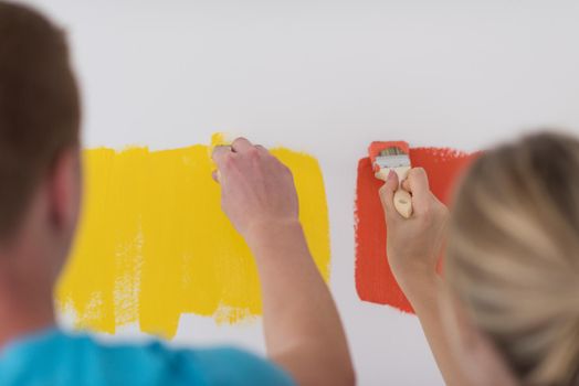 happy smiling young couple painting interior wall of new house