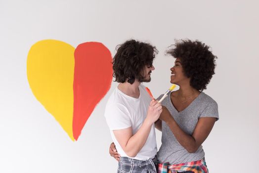 Portrait of loving multiethnict couple with painted heart on wall