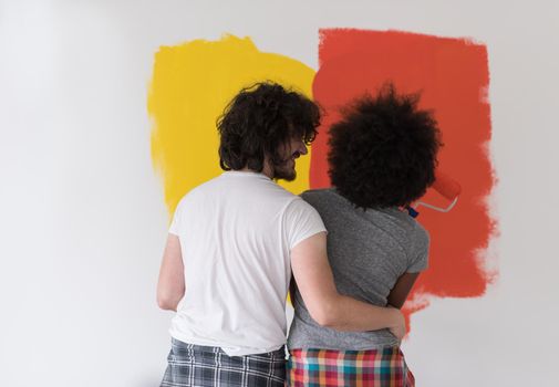 happy young multiethnic couple painting interior wall of new house