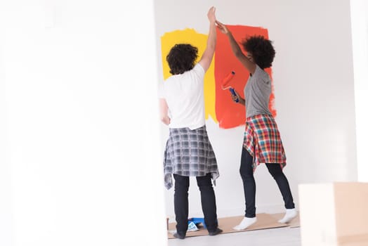 happy young multiethnic couple painting interior wall of new house