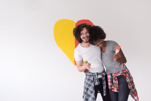 Portrait of loving multiethnict couple with painted heart on wall