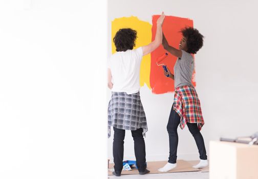 happy young multiethnic couple painting interior wall of new house