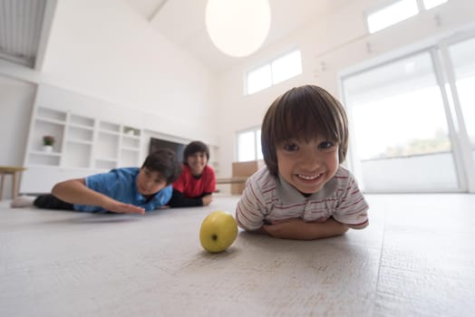 happy young boys having fun with an apple on the floor in a new modern home