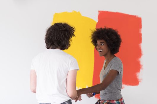 happy young multiethnic couple painting interior wall of new house