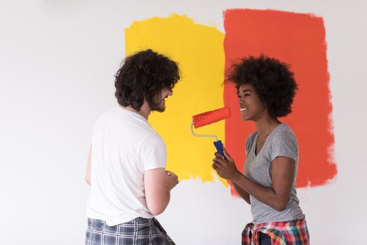 happy young multiethnic couple painting interior wall of new house