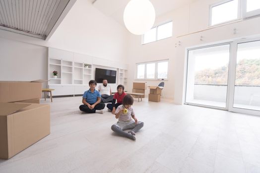 portrait of happy young boys with their dad sitting on the floor in a new modern home