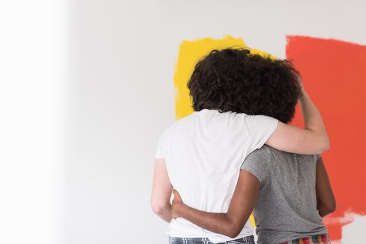 happy young multiethnic couple painting interior wall of new house