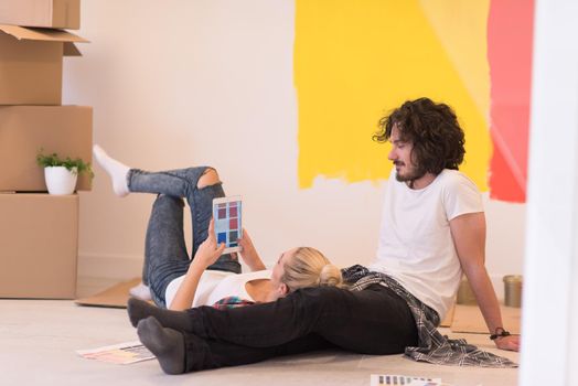 Happy young couple relaxing after painting a room in their new house on the floor