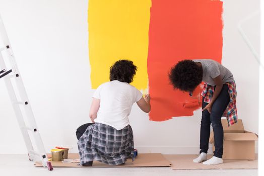 happy young multiethnic couple painting interior wall of new house