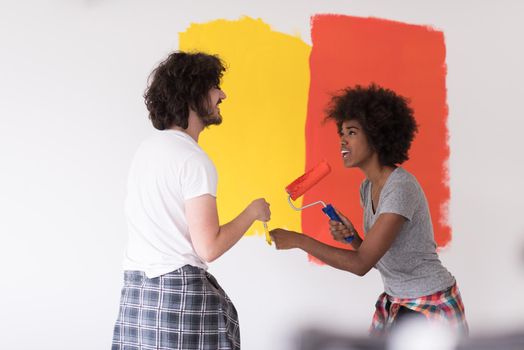 happy young multiethnic couple painting interior wall of new house