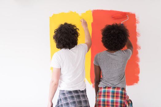 happy young multiethnic couple painting interior wall of new house