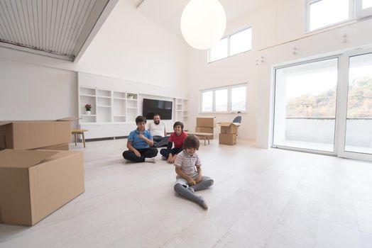 portrait of happy young boys with their dad sitting on the floor in a new modern home