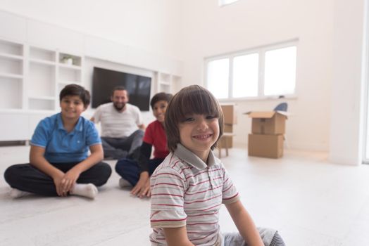 portrait of happy young boys with their dad sitting on the floor in a new modern home