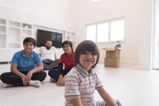 portrait of happy young boys with their dad sitting on the floor in a new modern home