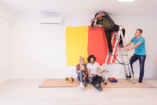 Happy young couple relaxing after painting a room in their new house on the floor