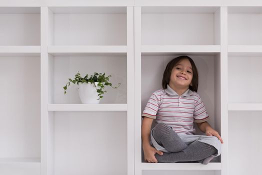 happy young boy having fun while posing on a shelf in a new modern home