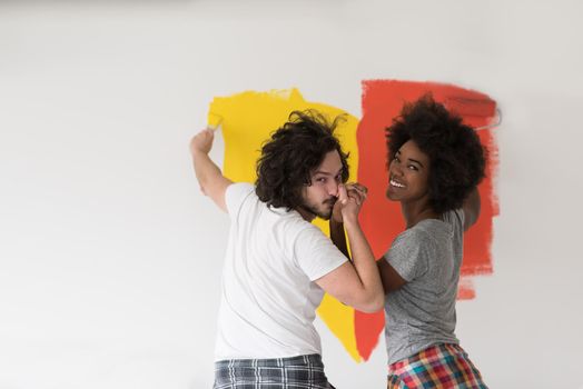 happy young multiethnic couple painting interior wall of new house