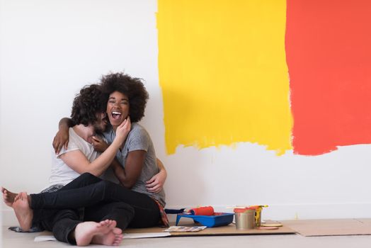 Happy young multiethnic couple relaxing after painting a room in their new house on the floor