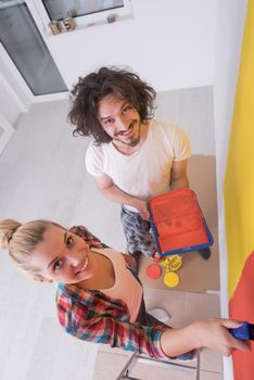 happy smiling young couple painting interior wall of new house