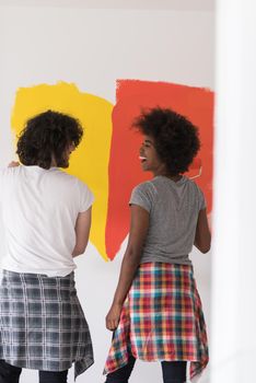 happy young multiethnic couple painting interior wall of new house