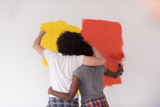 happy young multiethnic couple painting interior wall of new house