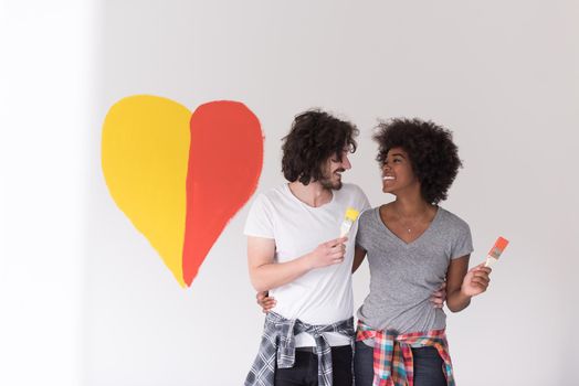 Portrait of loving multiethnict couple with painted heart on wall