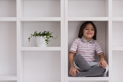 happy young boy having fun while posing on a shelf in a new modern home