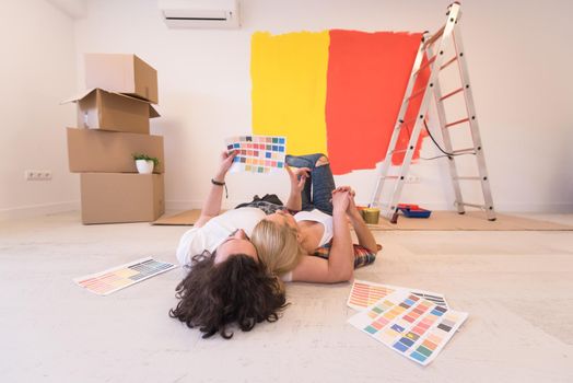 Happy young couple relaxing after painting a room in their new house on the floor