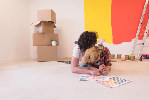 Happy young couple relaxing after painting a room in their new house on the floor