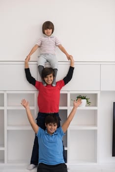 happy young boys having fun and posing line up piggyback in new modern home