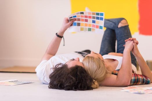 Happy young couple relaxing after painting a room in their new house on the floor