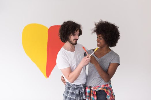 Portrait of loving multiethnict couple with painted heart on wall