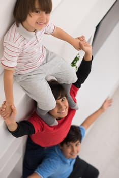 happy young boys having fun and posing line up piggyback in new modern home top view