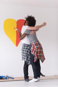 Portrait of loving multiethnict couple with painted heart on wall