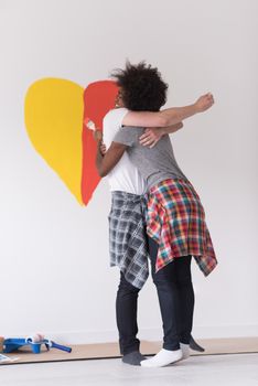 Portrait of loving multiethnict couple with painted heart on wall