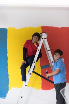 a group of young boys helps to paint a wall in new home