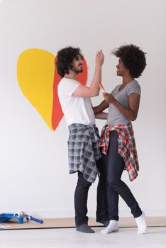 Portrait of loving multiethnict couple with painted heart on wall