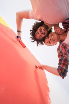 happy smiling young couple painting interior wall of new house