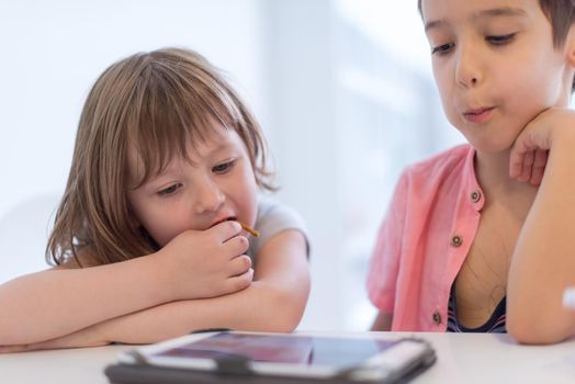 cute little brother and sister having fun at home childrends  playing games on tablet computer