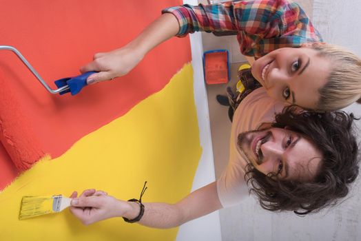 happy smiling young couple painting interior wall of new house