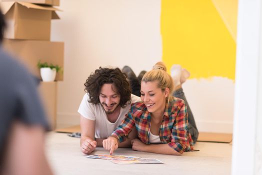 Happy young couple relaxing after painting a room in their new house on the floor