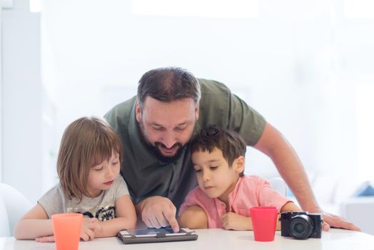single father at home with two kids playing games and giving education lessons on tablet  computer at modern home
