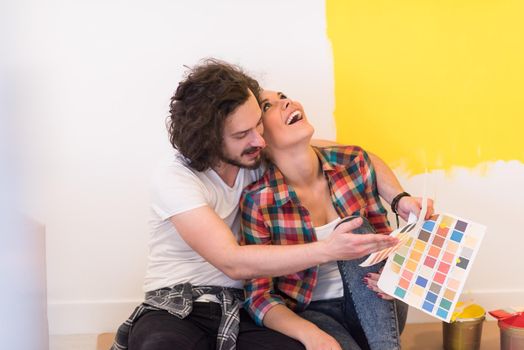 Happy young couple relaxing after painting a room in their new house on the floor