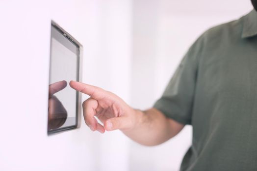 smart home and technology concept close up of male hands pointing finger to tablet pc computer integrated in house indoor wall