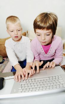 two happy children playing games and learnig education lessons on laptop computer at home